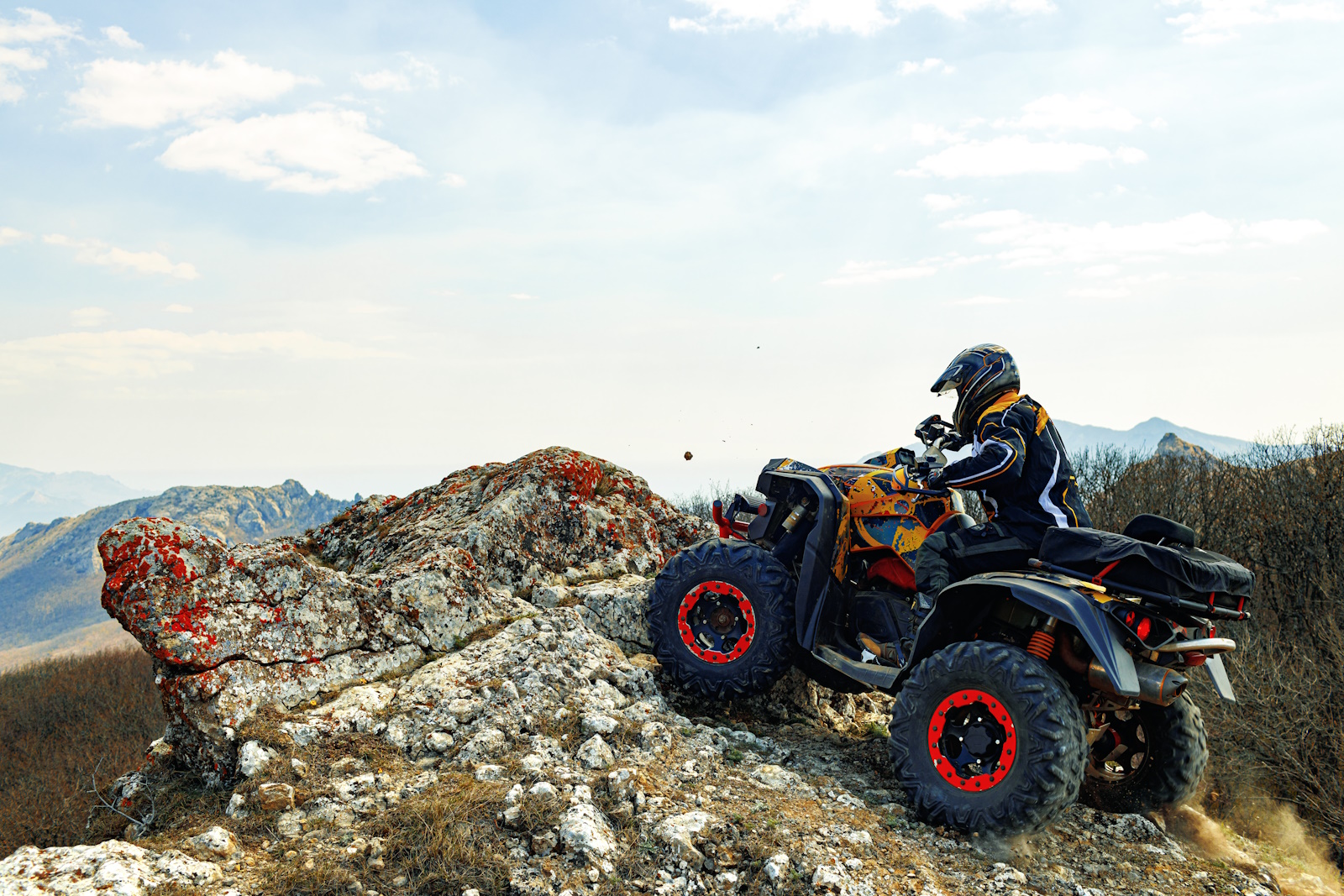 Man in helmet sitting on ATV quad bike in mountains on race